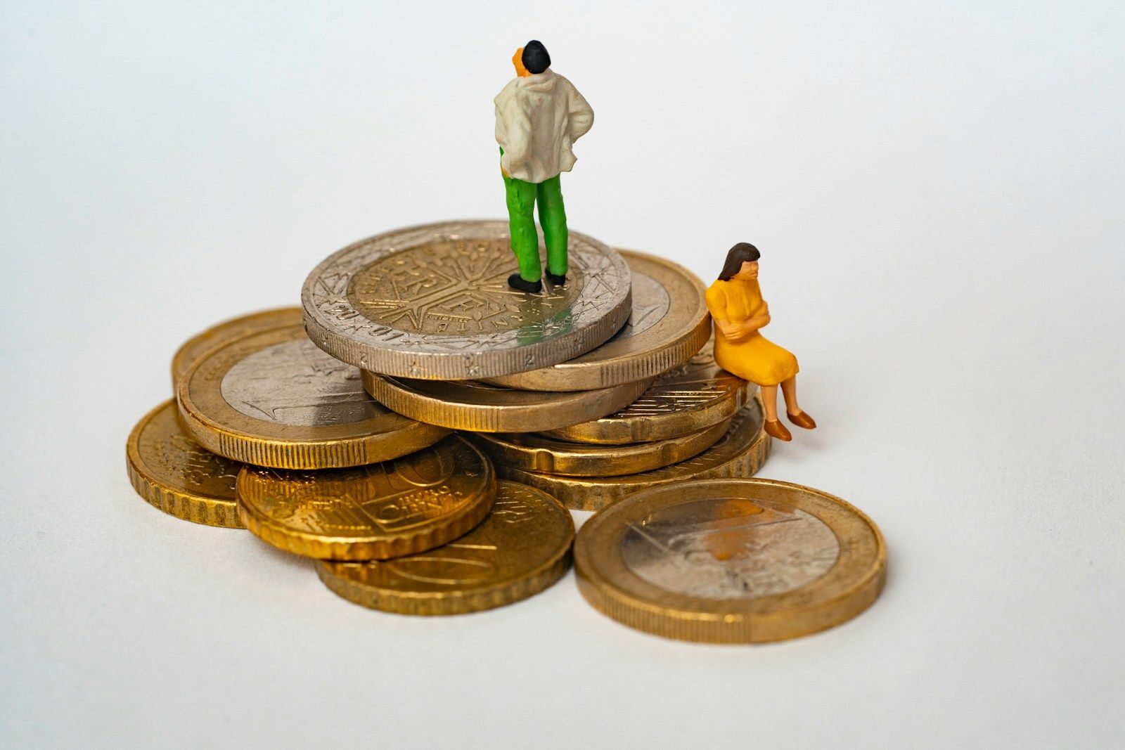 deux petits personnages assis sur des pièces de monnaie euros