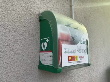 Photo d'un défibrillateur vert installé le long d'un mur.