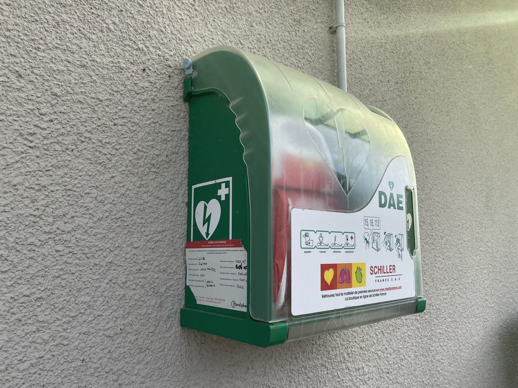 Photo d'un défibrillateur vert installé le long d'un mur.