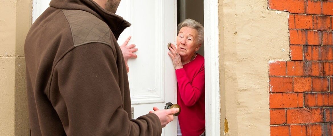 Démarchage à domicile. Une personne âgée ouvre la porte à une autre personne.