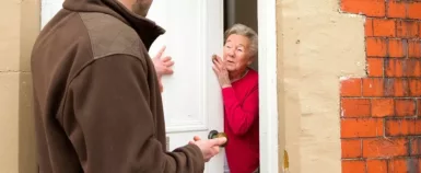 Démarchage à domicile. Une personne âgée ouvre la porte à une autre personne.