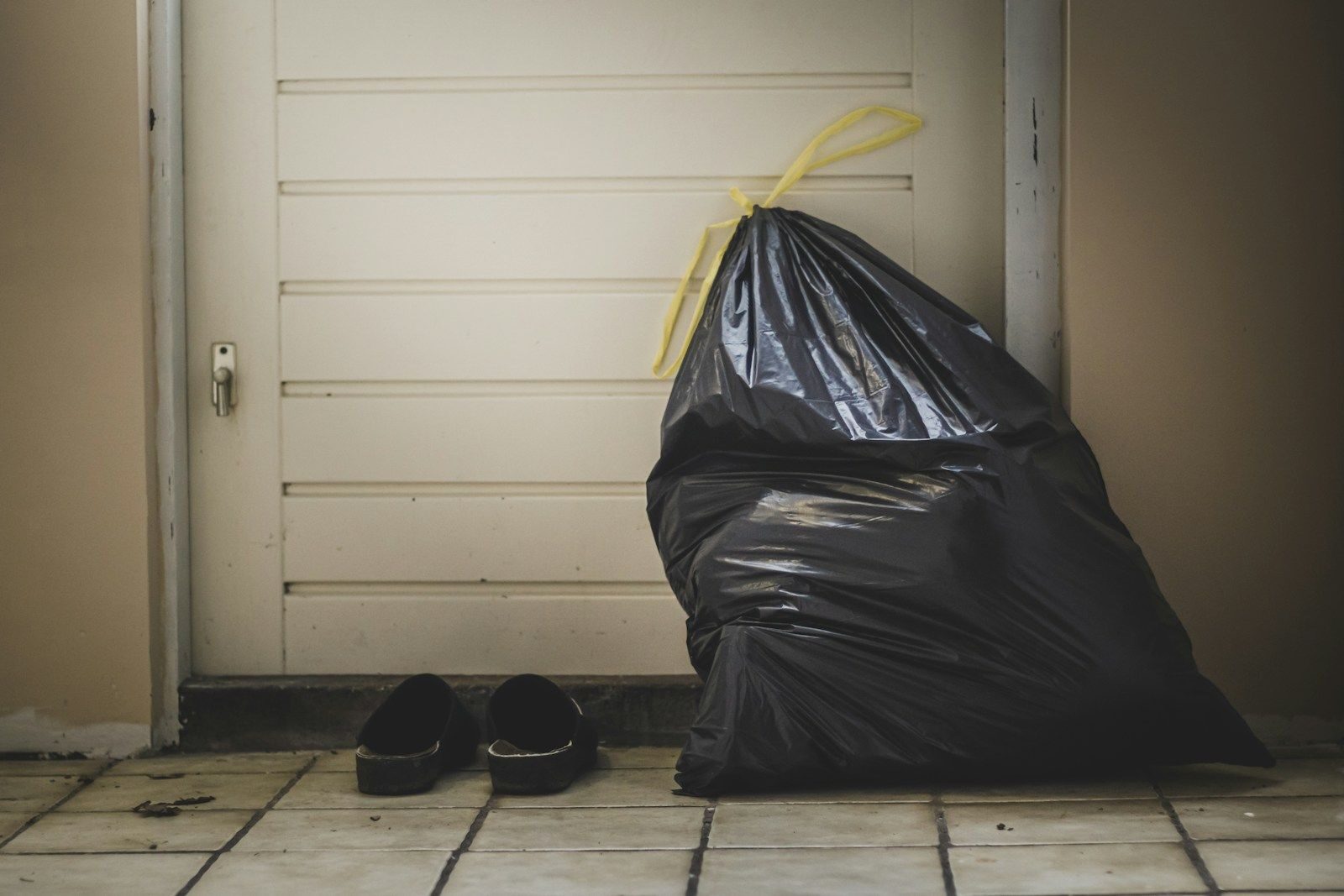 sac en plastique noir à côté d'un mur blanc