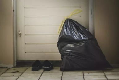 sac en plastique noir à côté d'un mur blanc