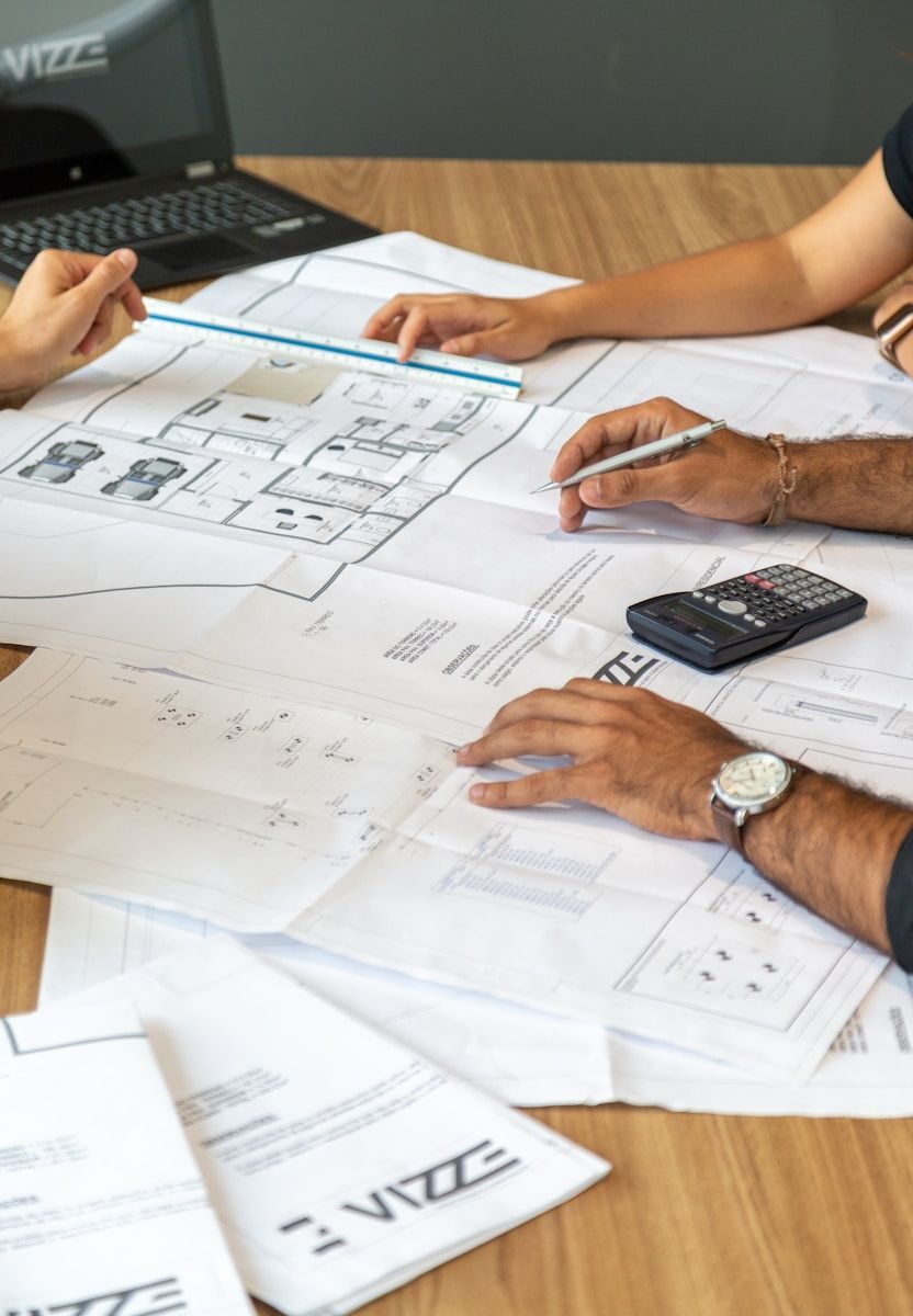 plusieurs mains sur une table avec des plans de construction