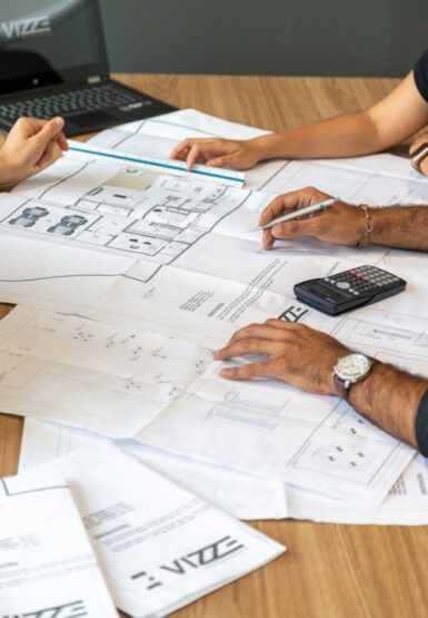 plusieurs mains sur une table avec des plans de construction