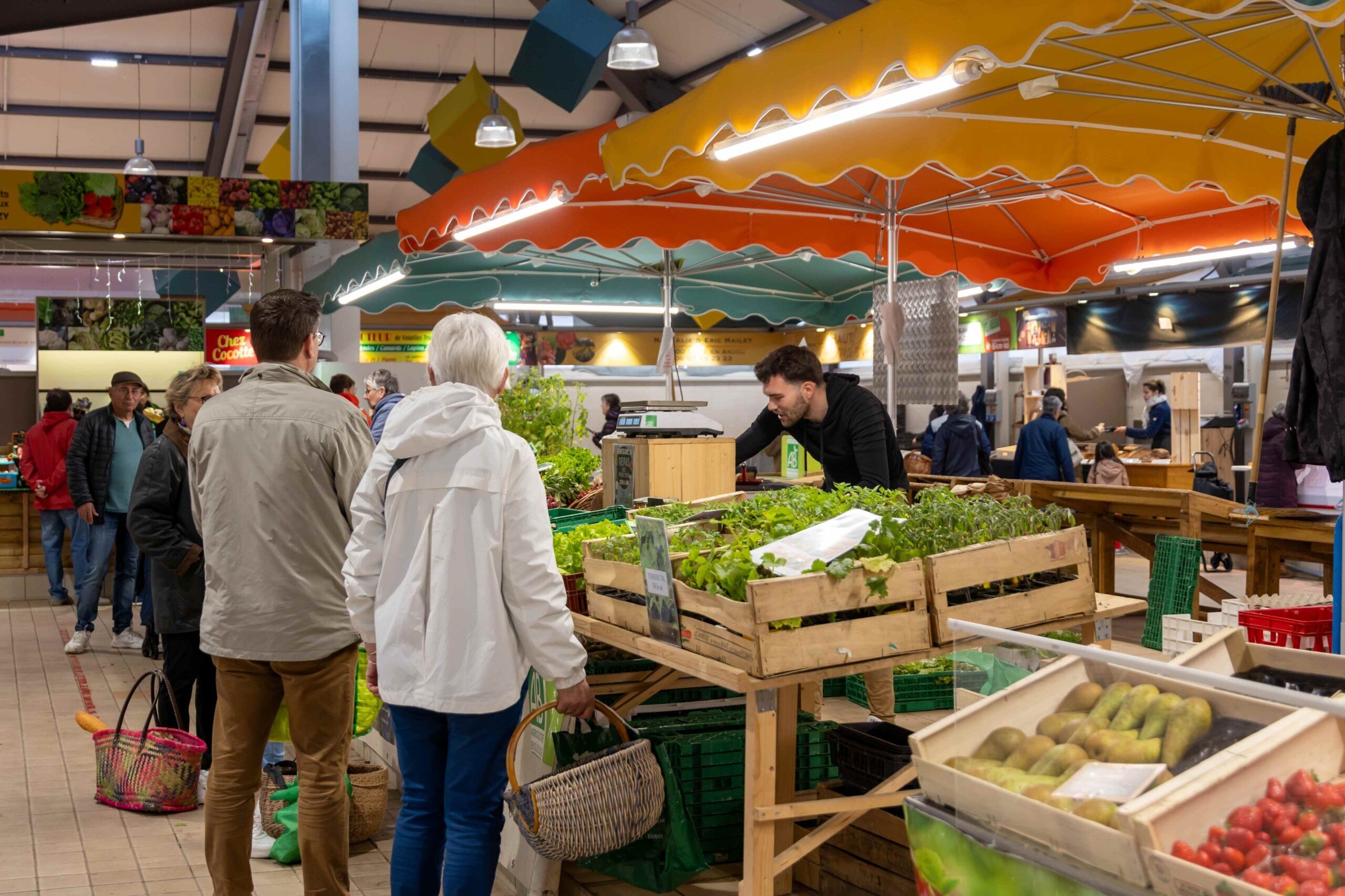 Intérieur du Marché des Saveurs avec des étales de fruits et légumes et des clients