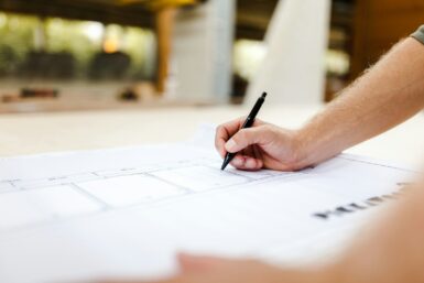 personne écrivant sur des plans de construction