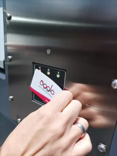 Photo d'une main utilisant une carte Agglo 2B pour déposer ses déchets dans un Point d'Apport Volontaire