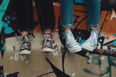 Deux jambes et chaussures converses le long d'un mur