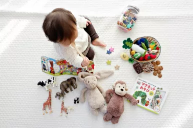 bébé sur un tapis de jeu avec des jouets et peluches