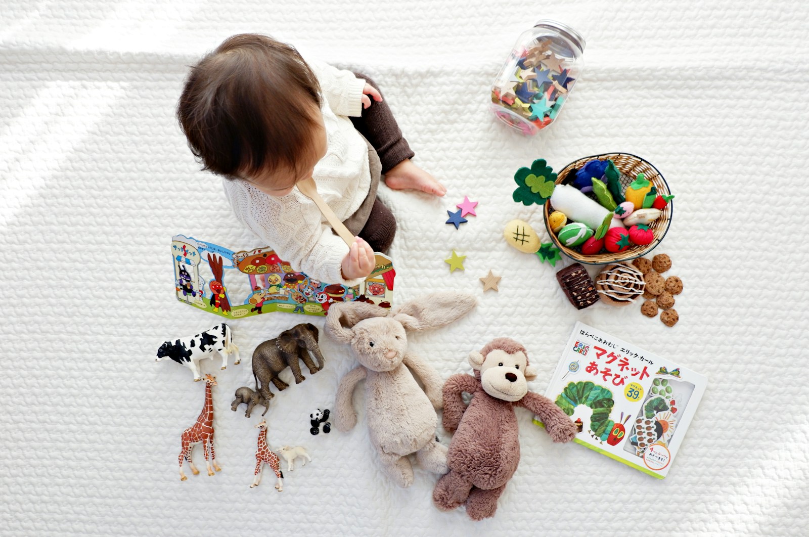 bébé sur un tapis de jeu avec des jouets et peluches