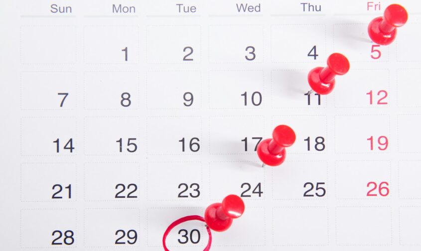 a calendar with red push buttons pinned to it